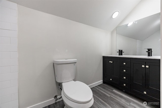 bathroom featuring vanity, wood-type flooring, lofted ceiling, and toilet