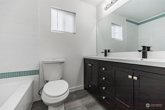 bathroom with a bath, vanity, wood-type flooring, and toilet