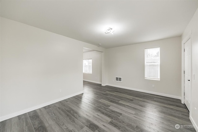 spare room featuring a healthy amount of sunlight and dark hardwood / wood-style floors