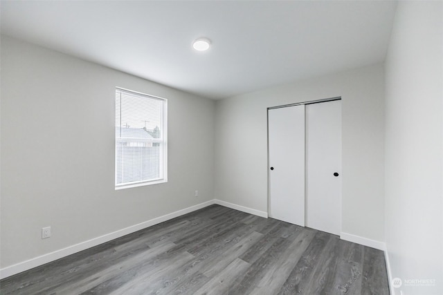 unfurnished bedroom featuring a closet and dark hardwood / wood-style floors