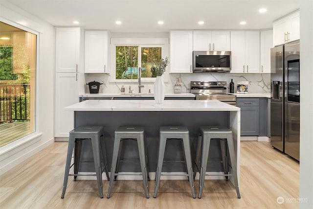 kitchen with a kitchen bar, white cabinetry, and appliances with stainless steel finishes