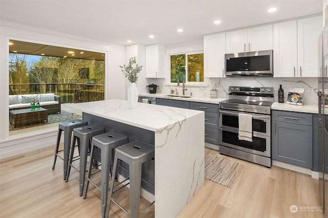 kitchen with appliances with stainless steel finishes, a center island, gray cabinets, and sink