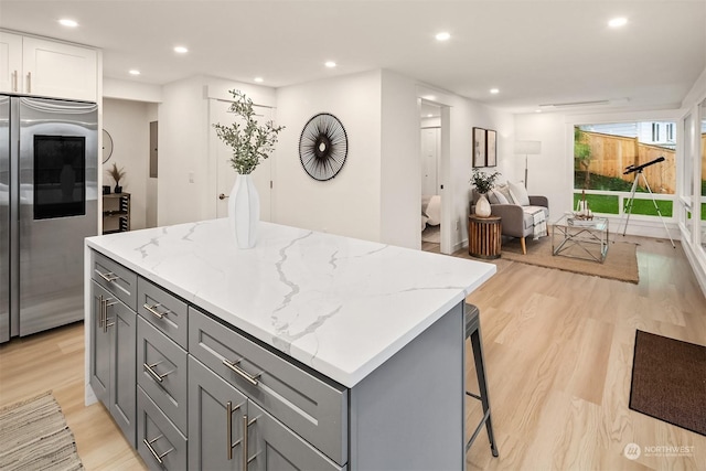 kitchen featuring gray cabinetry, built in fridge, light stone countertops, a kitchen island, and white cabinetry