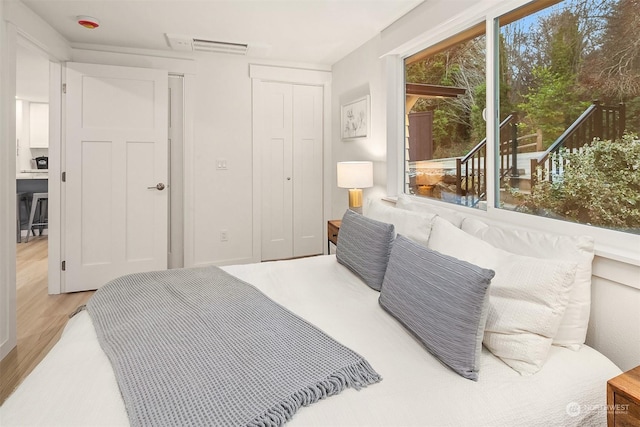 bedroom featuring access to outside, light hardwood / wood-style flooring, and a closet