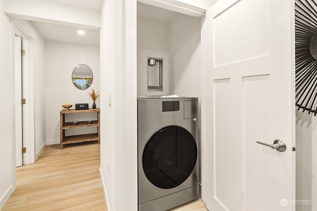 clothes washing area featuring washer / clothes dryer and light hardwood / wood-style flooring