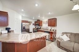 kitchen featuring lofted ceiling, stainless steel appliances, kitchen peninsula, and hanging light fixtures