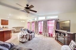 carpeted living room featuring vaulted ceiling and ceiling fan