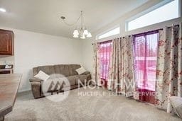 living room featuring light colored carpet, vaulted ceiling, and a notable chandelier