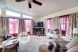 living room featuring vaulted ceiling, carpet flooring, and ceiling fan