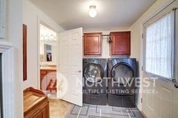 clothes washing area with cabinets and washer and dryer