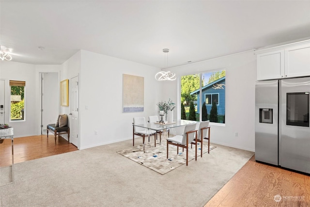 dining space featuring a wealth of natural light, light hardwood / wood-style floors, and an inviting chandelier