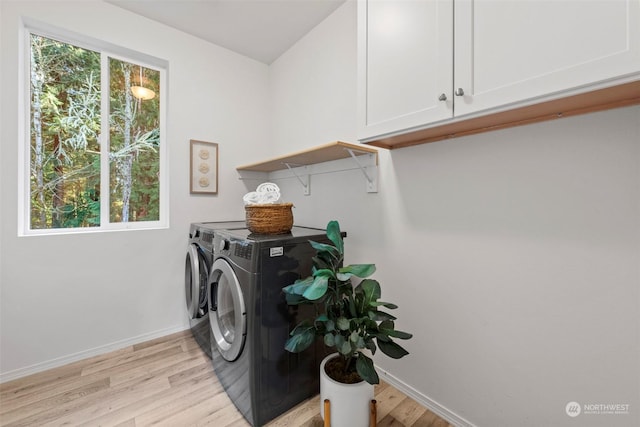 laundry room with cabinets, washer and clothes dryer, and light hardwood / wood-style floors