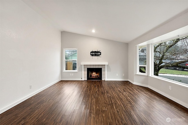 unfurnished living room featuring dark wood-type flooring, lofted ceiling, and a tile fireplace