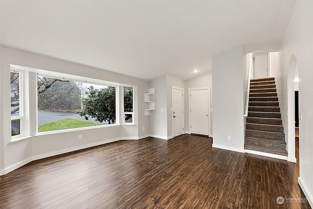 unfurnished living room featuring dark wood-type flooring and vaulted ceiling