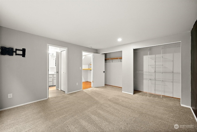 unfurnished bedroom featuring multiple closets, connected bathroom, and light carpet