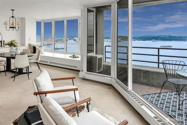 sunroom / solarium featuring a water view, a baseboard radiator, and a notable chandelier