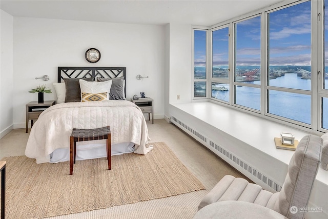 carpeted bedroom featuring baseboard heating and a water view