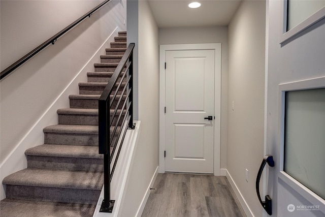 stairway with baseboards, wood finished floors, and recessed lighting