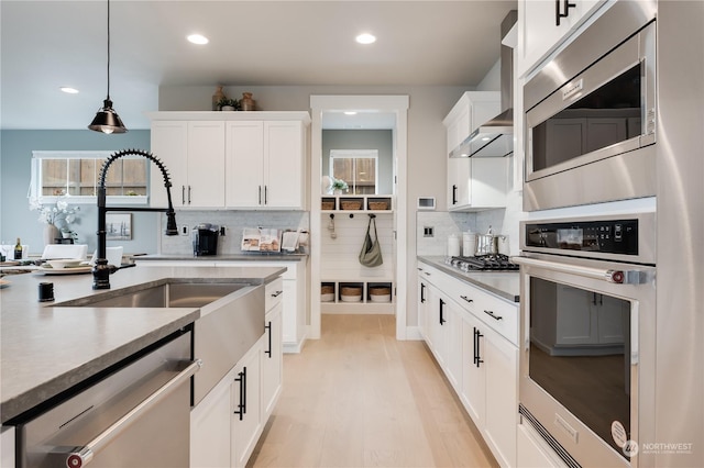 kitchen featuring decorative backsplash, appliances with stainless steel finishes, sink, pendant lighting, and white cabinetry