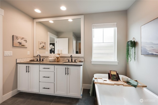 bathroom featuring tile patterned floors, vanity, a healthy amount of sunlight, and a tub to relax in