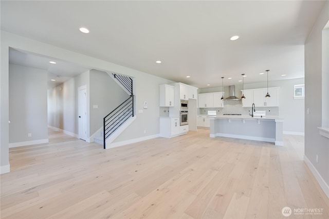 26521 NE 147th Pl Unit Sr 11, Duvall, WA 98019 - unfurnished living room featuring a sink, recessed lighting, light wood-style flooring, stairs, and baseboards