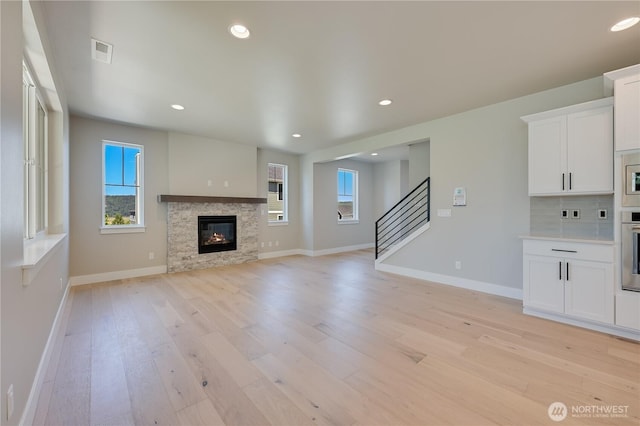 26521 NE 147th Pl Unit Sr 11, Duvall, WA 98019 - unfurnished living room with plenty of natural light, light wood-style flooring, baseboards, a glass covered fireplace, and recessed lighting