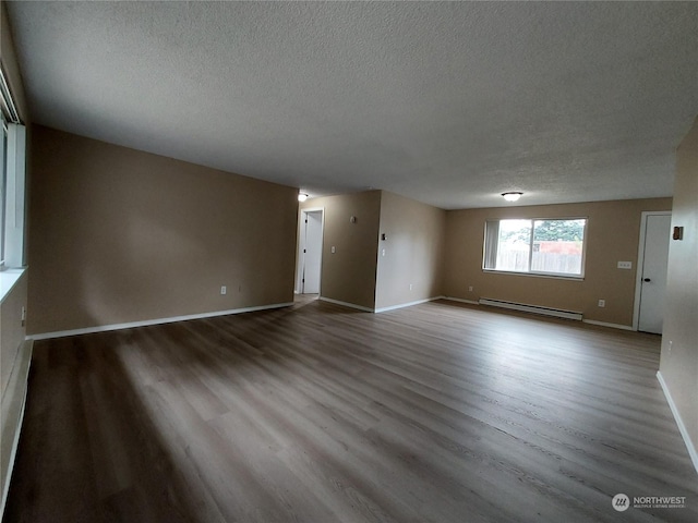 spare room with a textured ceiling, baseboard heating, and light wood-type flooring