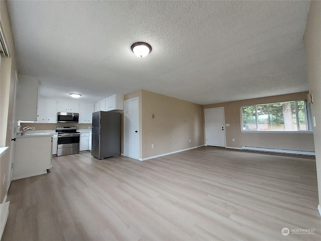 kitchen featuring a textured ceiling, stainless steel appliances, light hardwood / wood-style floors, baseboard heating, and white cabinets