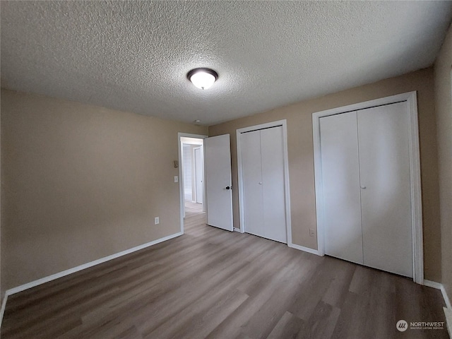 unfurnished bedroom with multiple closets, hardwood / wood-style floors, and a textured ceiling