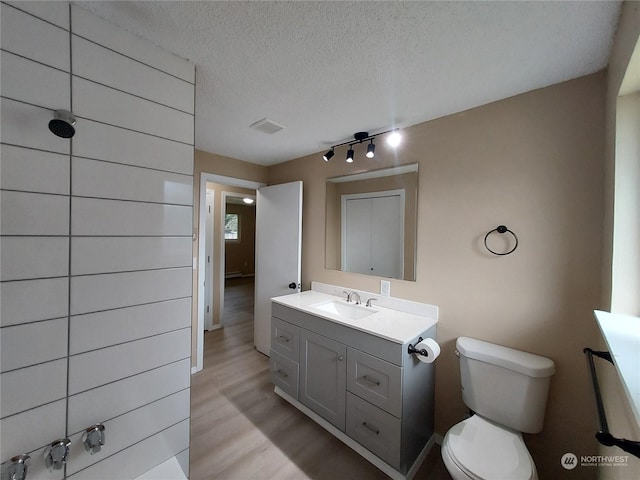 bathroom featuring toilet, hardwood / wood-style flooring, a textured ceiling, and vanity