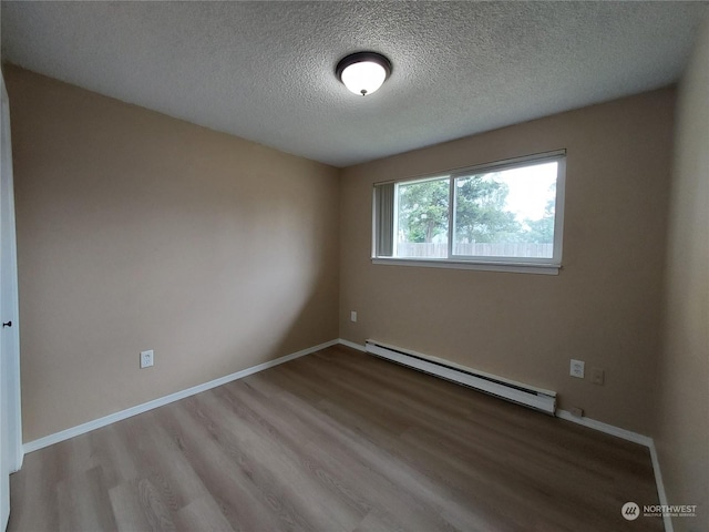 spare room with wood-type flooring, a baseboard heating unit, and a textured ceiling