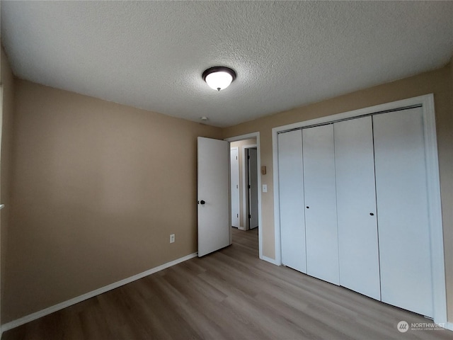 unfurnished bedroom featuring a textured ceiling, light hardwood / wood-style floors, and a closet