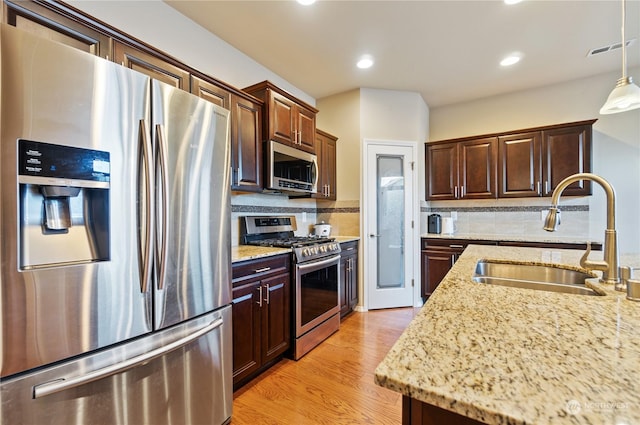 kitchen featuring sink, light stone counters, appliances with stainless steel finishes, and tasteful backsplash