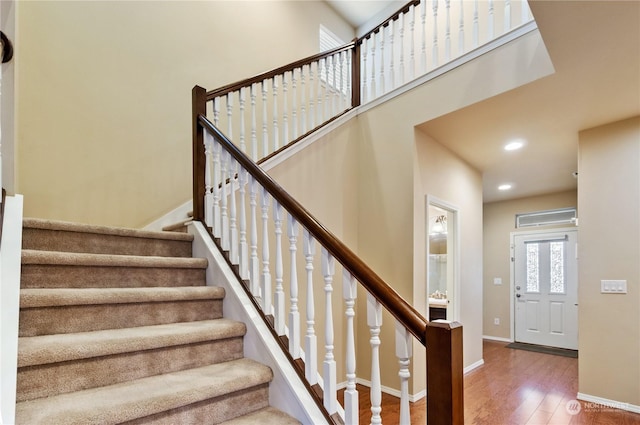 stairs with hardwood / wood-style flooring and a high ceiling