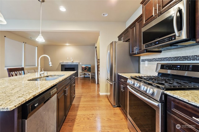 kitchen featuring pendant lighting, sink, an island with sink, light hardwood / wood-style floors, and stainless steel appliances