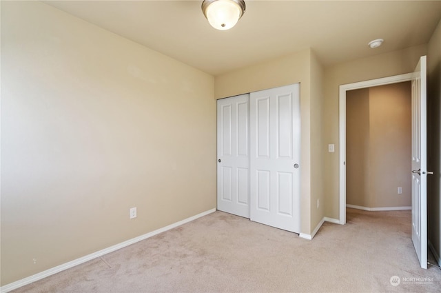 unfurnished bedroom featuring light colored carpet and a closet