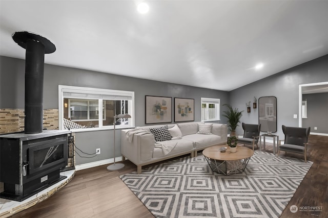 living room with a wood stove, wood-type flooring, and vaulted ceiling