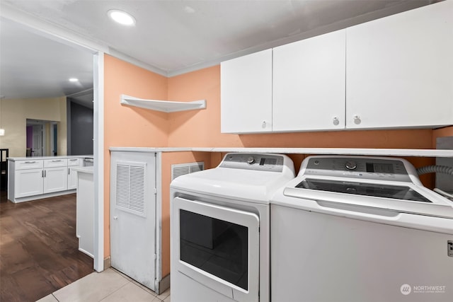 laundry area featuring washing machine and clothes dryer, light tile patterned floors, and cabinets