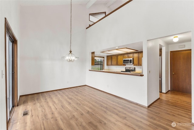 unfurnished living room featuring beam ceiling, a chandelier, high vaulted ceiling, and light hardwood / wood-style floors