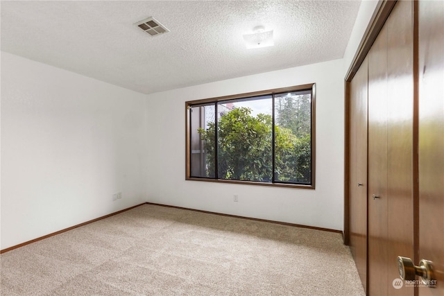 unfurnished bedroom featuring a closet, light colored carpet, and a textured ceiling