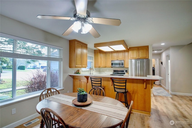 dining area with ceiling fan, sink, and light hardwood / wood-style flooring