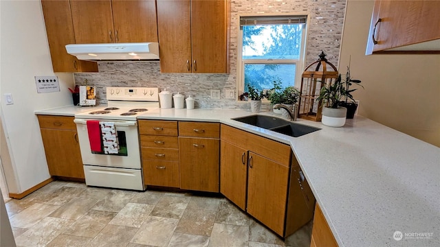 kitchen with electric stove, light countertops, backsplash, a sink, and under cabinet range hood