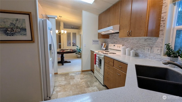 kitchen featuring white appliances, brown cabinets, light countertops, under cabinet range hood, and a sink