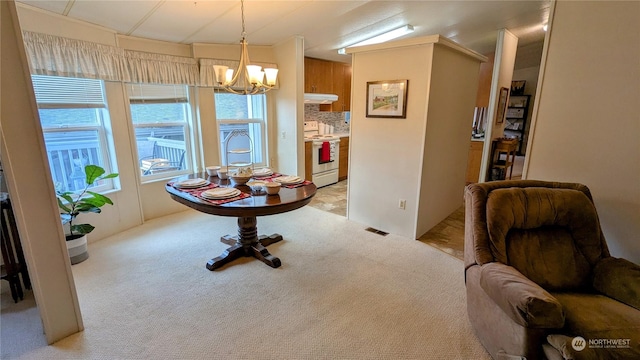 dining area with an inviting chandelier, visible vents, and light colored carpet