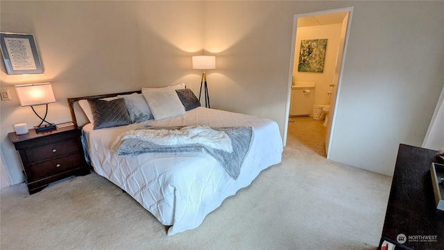 bedroom with ensuite bath and light colored carpet