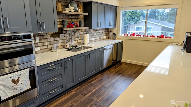 kitchen with gray cabinets, appliances with stainless steel finishes, tasteful backsplash, dark wood-type flooring, and sink