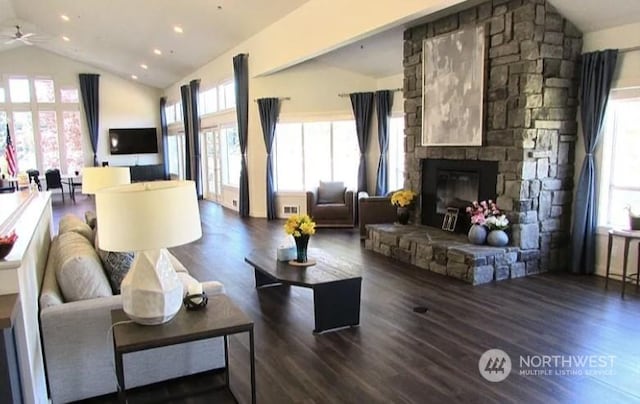 living room featuring dark wood-style floors, vaulted ceiling, visible vents, and a fireplace