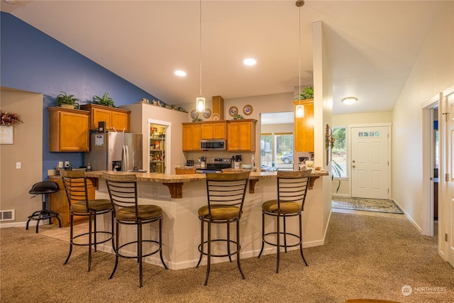 kitchen with kitchen peninsula, light carpet, a breakfast bar, stainless steel appliances, and vaulted ceiling