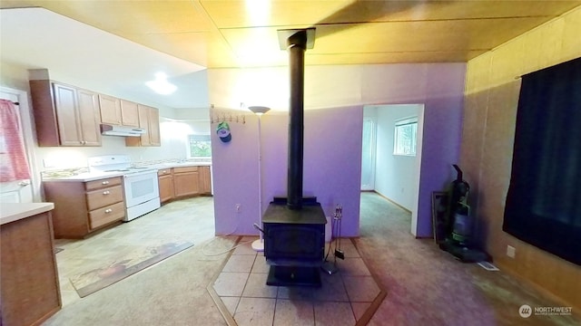 kitchen with light carpet, white electric stove, and a wood stove