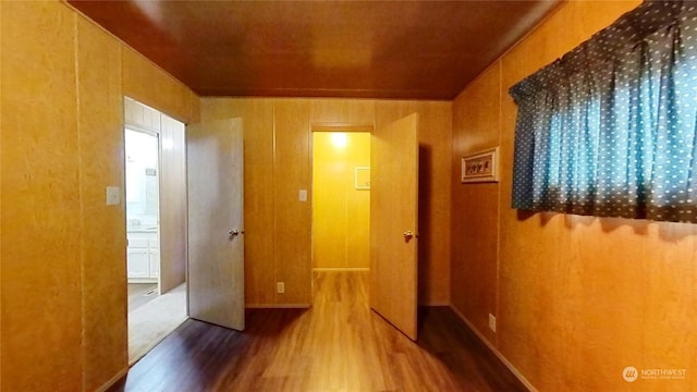 corridor with hardwood / wood-style flooring and wood walls